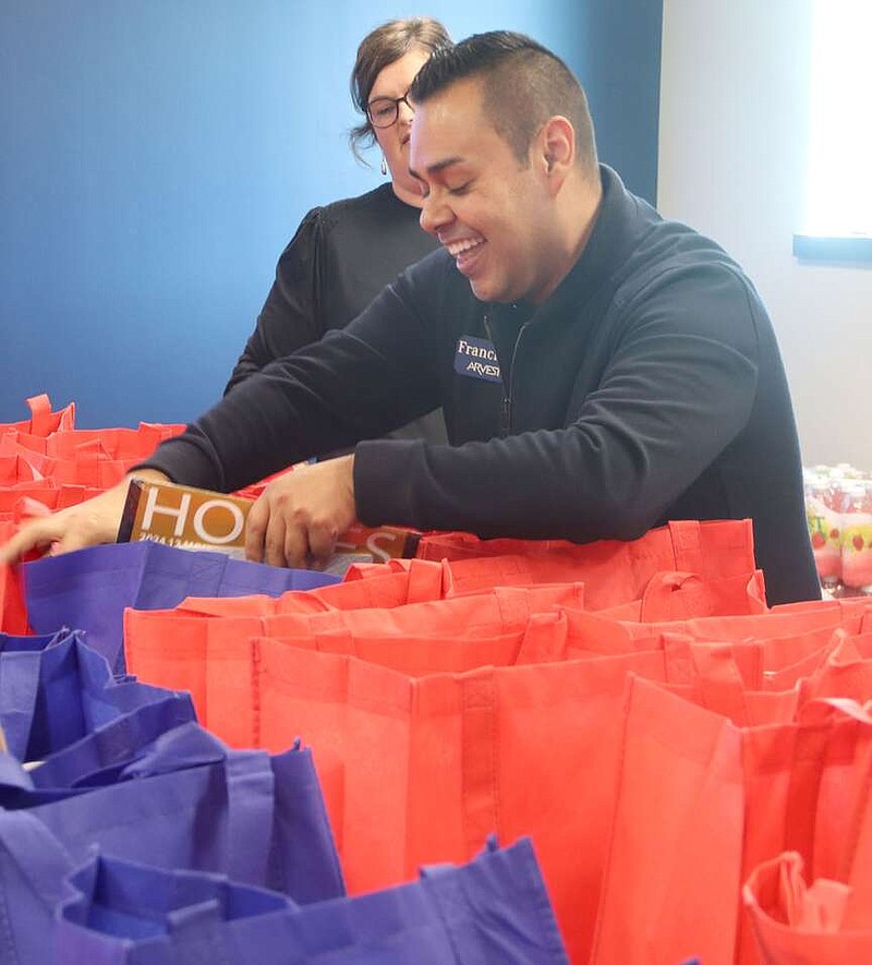 Lynn Kutter/Enterprise-Leader
Francisco Cortez, branch administrator with Arvest Bank for the Farmington, Prairie Grove, Lincoln, West Fork and Elkins branches, places gift items in these bags that will be delivered to the homebound who receive Meals on Wheels in this area.