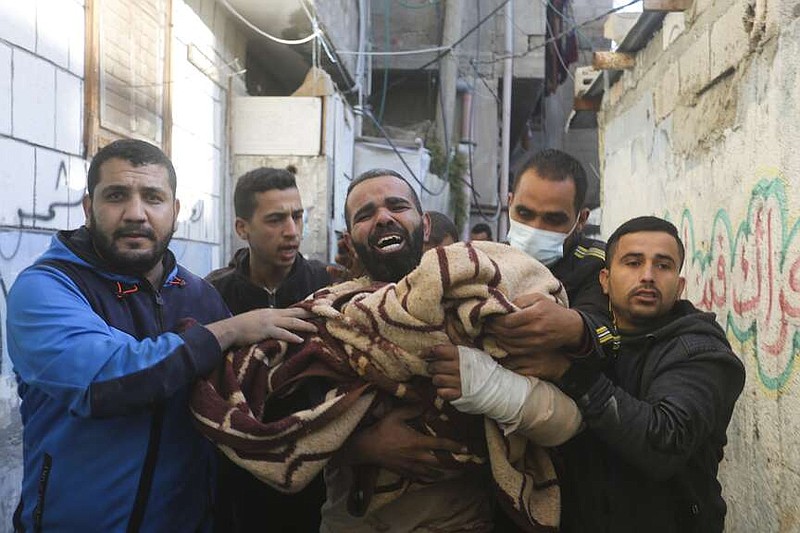 Palestinos cargan con un niño muerto en un bombardeo israelí sobre Rafah, en la Franja de Gaza, el 7 de diciembre de 2023. (AP Foto/Hatem Ali)