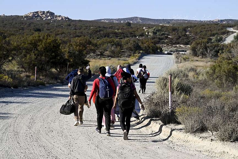 FILE - Asylum-seekers walk to a U.S. Border Patrol van after crossing the nearby border with Mexico, Tuesday Sept. 26, 2023, near Jacumba Hot Springs, Calif. Migrants continue to arrive to desert campsites along California's border with Mexico, as they await processing. Congress is discussing changes to the immigration system in exchange for providing money to Ukraine in its fight against Russia and Israel for the war with Hamas. (AP Photo/Denis Poroy, File)