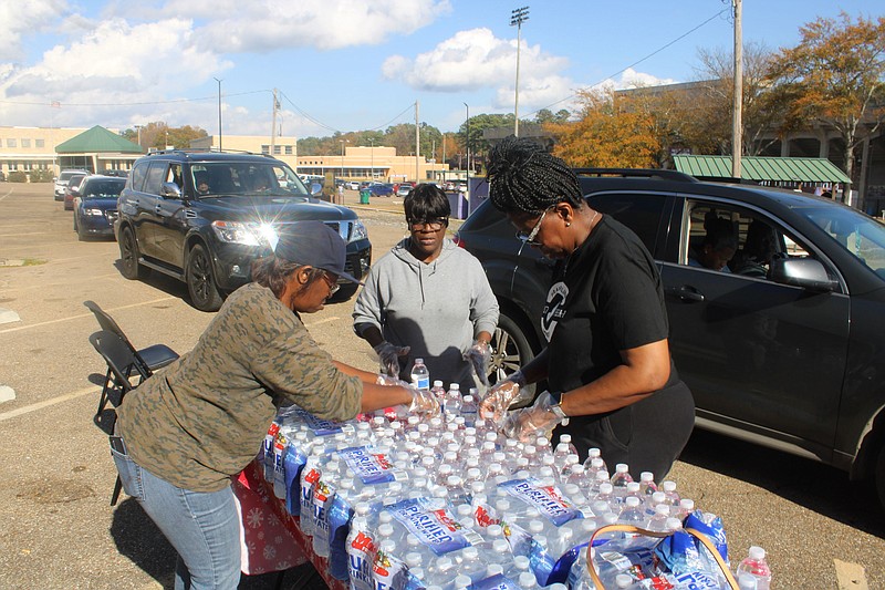 Anntionette Miller, Veronica Bailey and Carolyn Parker get waters ready to serve on Saturday during the Meet Me at the Court holiday dinner on Saturday. (Matt Hutcheson/News-Times)