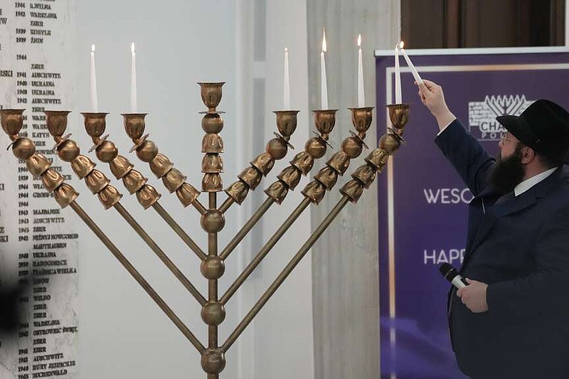 A rabbi lights candles of a menorah again after an incident in which a far-right lawmaker put out the candles, in Warsaw, Poland, on Tuesday, Dec. 12, 2023. The speaker of the parliament, Szymon Holownia, denounced the incident that was carried out by Grzegorz Braun on Tuesday, and said there would be no tolerance for antisemitic and xenophobic behavior in the Sejm, the Polish parliament.  (AP Photo/Czarek Sokolowski)
