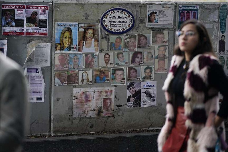 ARCHIVO - Una mujer pasa por delante de fotografías de personas desaparecidas frente a la procuraduría en Ciudad de México, el 6 de diciembre de 2023. (AP Foto/Eduardo Verdugo, archivo)