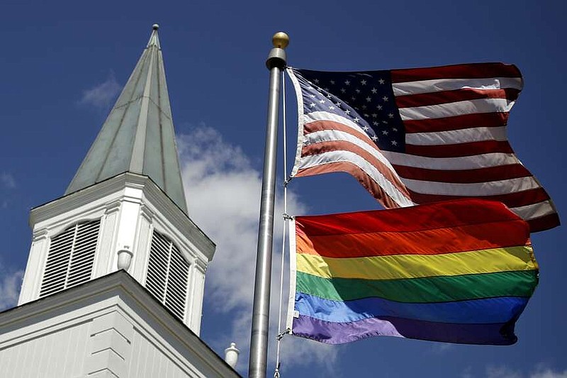 A gay pride rainbow flag flies along with the U.S. flag in front of the Asbury United Methodist Church on April 19, 2019, in Prairie Village, Kan. A quarter of U.S. congregations in the United Methodist Church have received permission to leave the denomination during a five-year window, closing in December 2023, that authorized departures for congregations over disputes involving the church's LGBTQ-related policies. (AP Photo/Charlie Riedel, File)
