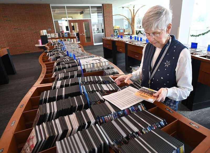 Laura Pasley, a 9-year volunteer at the Fayetteville Public Library, collects media items Thursday, Dec. 14, 2023, for patronsâ€™ hold requests at the library. The libraryâ€™s board approved its budget for next year on Monday. Visit nwaonline.com/photo for today's photo gallery.
(NWA Democrat-Gazette/Andy Shupe)