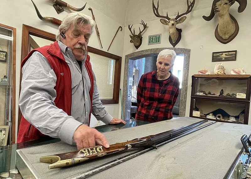 Eureka Springs Mayor Robert “Butch” Berry delivers a rifle from his brother's collection to Saunders Memorial Museum in Berryville on Monday. C. Burton Saunders, founder of the museum, gave the rifle to Berry's brother, Michael Pierce, about 70 years ago, when Pierce was working — mostly “sweeping up” — in the museum. At that time, the gun was in pieces, and Saunders restored it. Pierce, 82, died in October, and Berry said he wanted to return the gun to the museum. Berryville City Council member Linda Riddlesperger, who volunteers at the museum, is also pictured.
(Arkansas Democrat-Gazette/Bill Bowden)