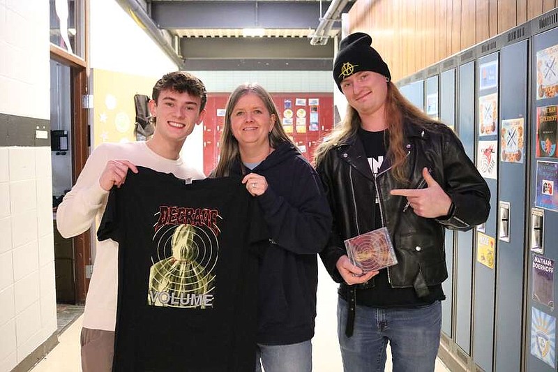 Anna Campbell/News Tribune photo: 
Eugene High School graduates and brothers Devin Volmert and Dylan Volmert, left and right, pose with merchandise from Dylan's band Degrave. Younger brother Devin drew the art for the album cover in Rhonda Burkett's (center) high school art class. The Volmerts stopped by the school to drop off a t-shirt for Burkett and catch up.