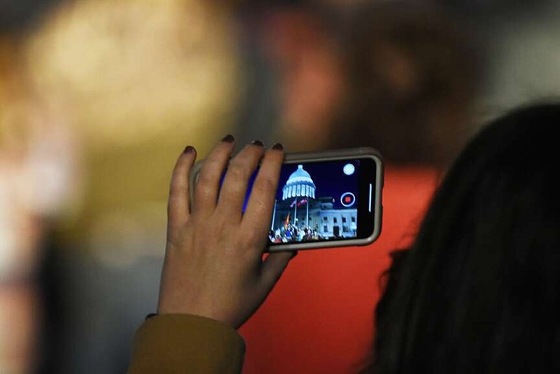 A spectator gets ready to take a video of the Arkansas State Capitol Christmas Lighting Ceremony on Saturday, Dec. 3, in Little Rock. (Arkansas Democrat-Gazette/Staci Vandagriff)
