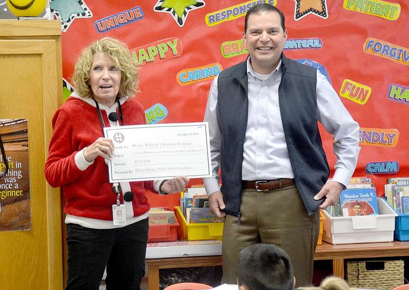 Marc Hayot/Herald-Leader Randy Torres (right), a member of the Siloam Springs Public School Foundation, presents third-grade teacher Denise Wilmott with a check for $1,073 on Dec. 18. Wilmott's project was External Monitors for use with Small Group Literacy Instruction.