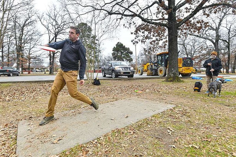 Elliott Bell (left), plays disc golf with Dale Haralson, both of Fort Smith, and dog Auggie, Thursday, Dec. 21, 2023, at Tilles Park in Fort Smith. Improvements to the park, including construction of an asphalt walking trail, drainage improvements and construction on the basketball court and disc golf tees, are currently underway and expected to be completed in May 2024. Visit rivervalleydemocratgazette.com/photo for todayâ€™s photo gallery.
(River Valley Democrat-Gazette/Hank Layton)