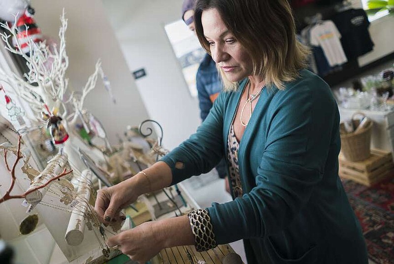 Oil + Meg Owner Nikki Spurlock picks up a necklace to show a customer, Friday, December 22, 2023 at Oli + Meg in Bentonville. Visit nwaonline.com/photos for today's photo gallery.

(NWA Democrat-Gazette/Charlie Kaijo)