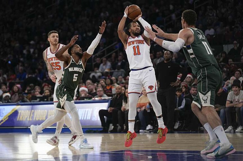 New York Knicks' Jalen Brunson (11), second from right, puts up a shot over Milwaukee Bucks' Brook Lopez, right, during the first half of an NBA basketball game, Monday, Dec. 25, 2023, in New York. (AP Photo/Seth Wenig)