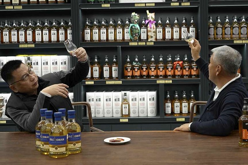 In this image from a video, Raymond Lee, founder of Single Malt Club China, right, samples whisky at a whisky store in Beijing on Dec. 9, 2023. Raymond Lee, founder of the Single Malt Club China, a whisky trading and distribution company established in Beijing in 2005, said whisky has become more popular as the economy has grown. (AP Photo/Caroline Chen)