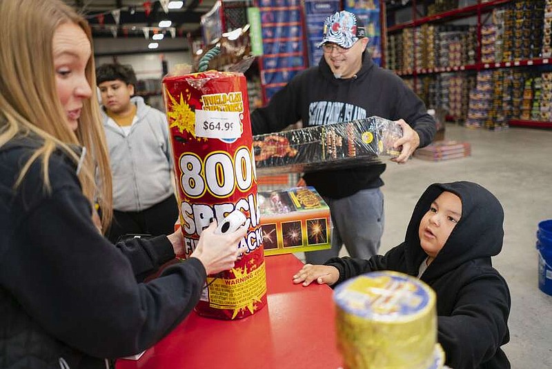 Pedero Martinez (bottom right), 3, talks to Linsey Crase as his family buys fireworks Thursday at Jake's Fireworks in Centerton. “We have people who travel from Missouri, Washington County and even from Siloam Springs. We're one of the only places that are open for New Year's,” said Blake Almond, who helps run the shop with his family. “It's just not a very wide selection of fireworks for that short amount of time, three to five days, that people are able to sell.” He added that even their second location in the former Bethel Heights can no longer sell fireworks since being annexed by Springdale due to that city's stricter regulations. Visit nwaonline.com/photos for today's photo gallery.

(NWA Democrat-Gazette/Charlie Kaijo)