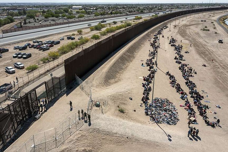 ARCHIVO - Migrantes forman filas frente a la valla en la frontera de Estados Unidos con México a la espera de ser transportados a una instalación de la Patrulla Fronteriza, el 10 de mayo de 2023, en El Paso, Texas. (AP Foto/Andrés Leighton, Archivo)
