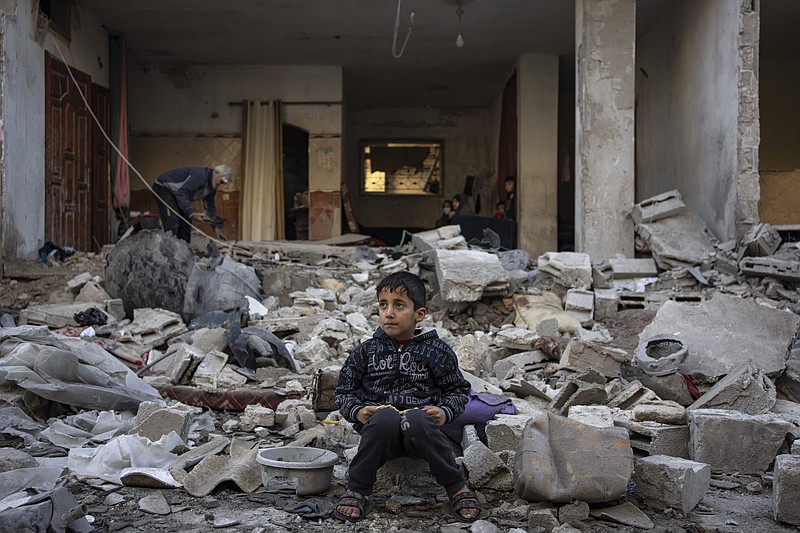 A Palestinian boy sits on the rubble of a destroyed building after an Israeli strike in Rafah, southern Gaza Strip, Friday, Dec. 29, 2023. (AP Photo/Fatima Shbair)