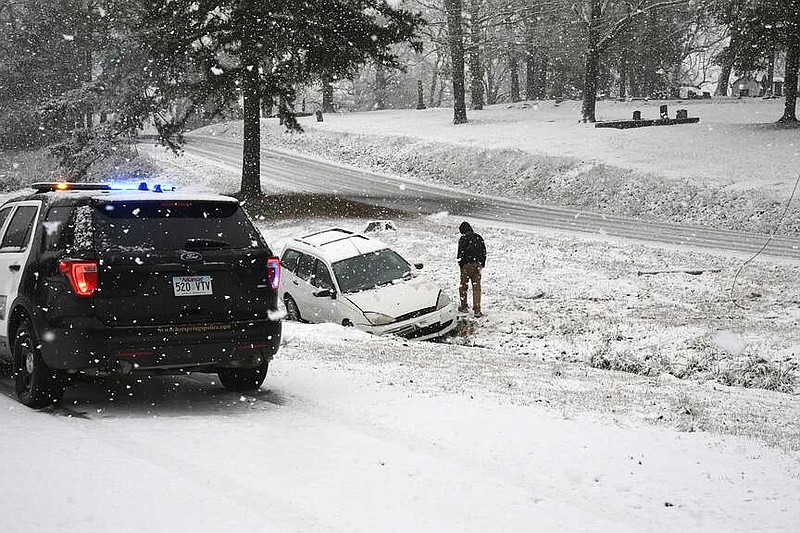 A motorist looks at his vehicle after it slid off Hollywood Road into the ditch on the north side of the road, near Friendship Cemetery. (The Sentinel-Record/Lance Brownfield)