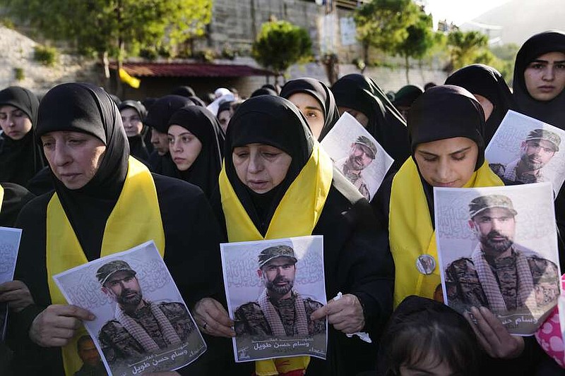Mourners hold portraits of senior Hezbollah commander Wissam Tawil during his funeral procession in the village of Khirbet Selm, south Lebanon, Tuesday, Jan. 9, 2024. The elite Hezbollah commander who was killed in an Israeli airstrike Monday in southern Lebanon fought for the group for decades and took part in some of its biggest battles. (AP Photo/Hussein Malla)