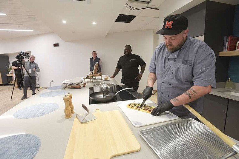 Jeff Beech (right) cuts pizza on Wednesday in the kitchen classroom at Walton Family Whole Health and Fitness. It's the first amenity to open at the new Walmart Home Office under construction in Bentonville. Go to nwaonline.com/photos for today's photo gallery.
(NWA Democrat-Gazette/Flip Putthoff)