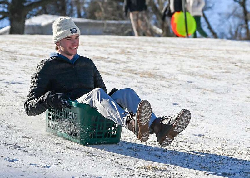 Trent Schroeder sleds down a hill on Wednesday at Wilson Park in Fayetteville. Schroeder, a student at the University of Arkansas, did not have his own sled, so he improvised by using a laundry basket. Snow and ice buildup has yet to melt after last Sunday's snowfall. Visit nwaonline.com/photo for today's photo gallery.
(NWA Democrat-Gazette/Caleb Grieger)
