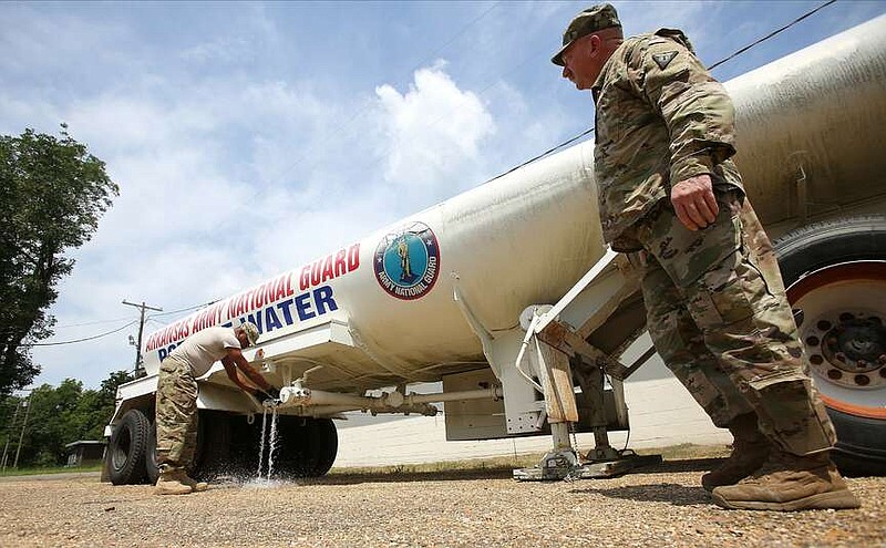 Master Sgt. Silas Owens (left) and Chief Warrant Officer Robert Jett (right) both with the Arkansas National Guard tests water valves on a trailer with 5,000 gallons of fresh water they had dropped off for residents of Carthage on Friday, Aug. 2, 2019.
(Arkansas Democrat-Gazette/THOMAS METTHE )