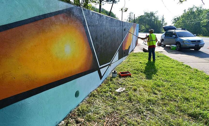 Artist Jeremy Navarrette of Springdale paints a mural in May 2022 on a retaining wall along Nelson Hackett Boulevard in Fayetteville. The city's Arts Council is working with a consulting firm to come up with an arts and culture master plan for the city.
(File photo/NWA Democrat-Gazette/Andy Shupe)