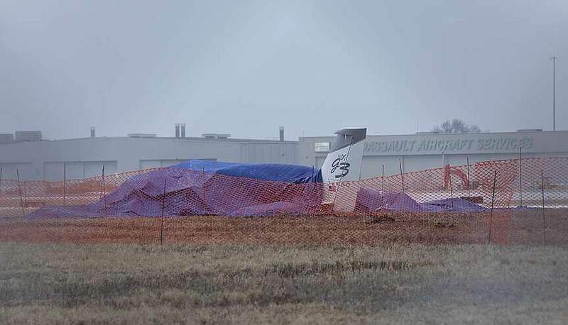 The wreckage of a single-engine Cirrus SR 22 aircraft is covered by a blue tarp near a runway at the Bill and Hillary Clinton National Airport on Monday, Jan. 22, 2024,  after it crashed on Sunday in Little Rock, Ark.  The pilot of the aircraft was pronounced dead at the scene and was the only individual on board at the time of the incident. (Colin Murphey  /Arkansas Democrat-Gazette via AP)