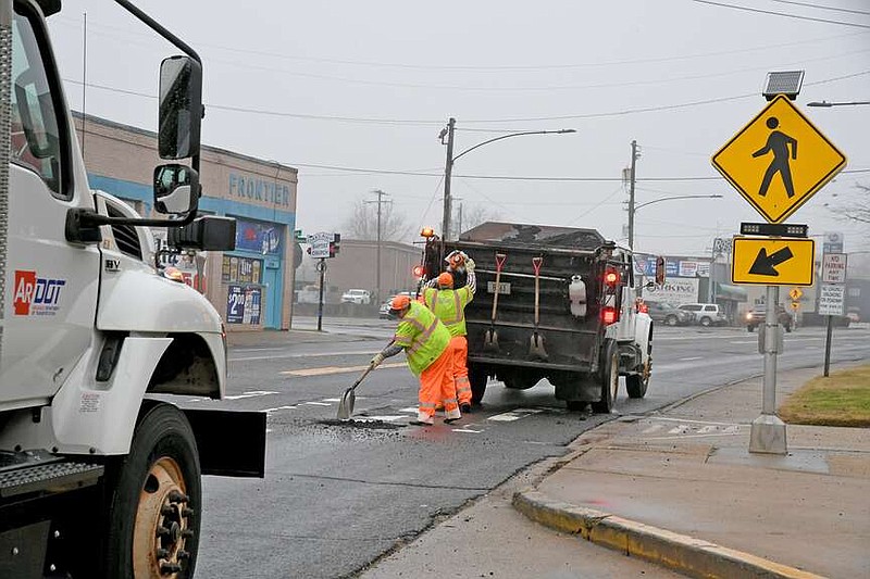 Workers with the Arkansas Department of Transportation fill a large pothole on Central Avenue near Oaklawn Racing Casino Resort and Crosswalk Bar and Club Wednesday morning. (The Sentinel-Record/Lance Brownfield)