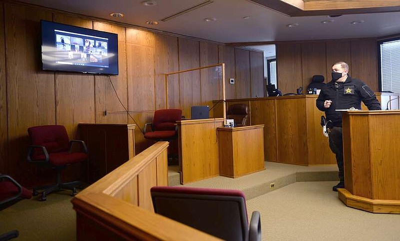 Deputy First Class James Rose with the Washington County Sheriff's Office monitors the progress Friday, Feb. 19, 2021, of arraignment hearings being held via a teleconferencing program on a monitor in Judge Mark Lindsay's courtroom in the Washington County Courthouse in Fayetteville.  (NWA Democrat-Gazette/Andy Shupe)