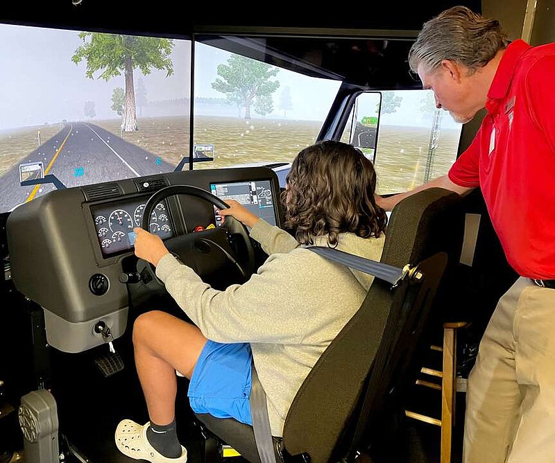 Randy Moll/Westside Eagle Observer
Gentry sophomore Jayden Knox sits behind the wheel of a truck-driving simulator, with Brett McBain watching over him, at Gentry High School on Jan. 24. The simulator was brought to the school by the Arkansas Trucking Association to give students considering a driving career the opportunity to test their skills.