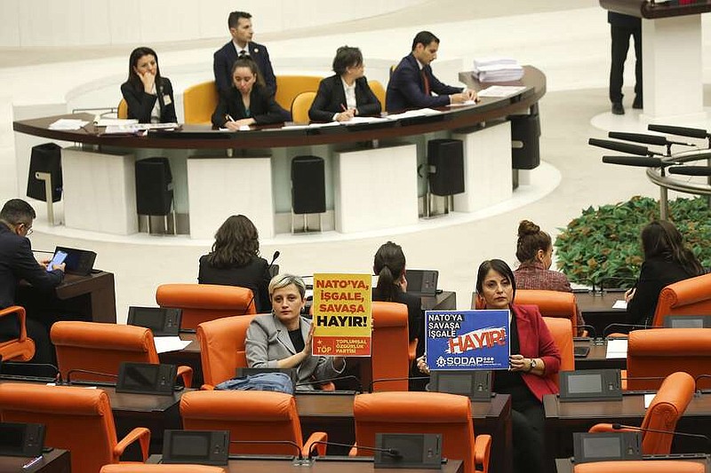 Turkish lawmakers from Toplumsal Ozgurluk or Social Freedom party, foreground left, and Sosyalist Dayanisma Platformu or Socialist Solidarity Platform hold posters that read in Turkish: "No occupation, no war for Nato!" during the debate of Sweden's bid to join NATO at the Turkish Parliament in Ankara, Turkey, Tuesday, Jan. 23, 2024. Turkish legislators on Tuesday endorsed Sweden's membership in NATO, lifting a major hurdle on the previously nonaligned country's entry into the military alliance. (AP Photo/Ali Unal)