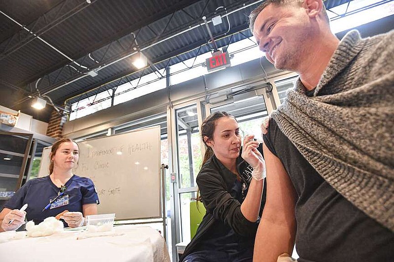 Shane Jennings (from right), a parent of a Future School of Fort Smith student, receives a flu shot from University of Arkansas at Fort Smith nursing students Bethany Willmann and Kassy Pense at a free community flu clinic hosted by the Arkansas Department of Health's Sebastian County Health Unit inside the Future School's teacher lounge in Fort Smith. (File Photo/NWA Democrat-Gazette/Hank Layton)