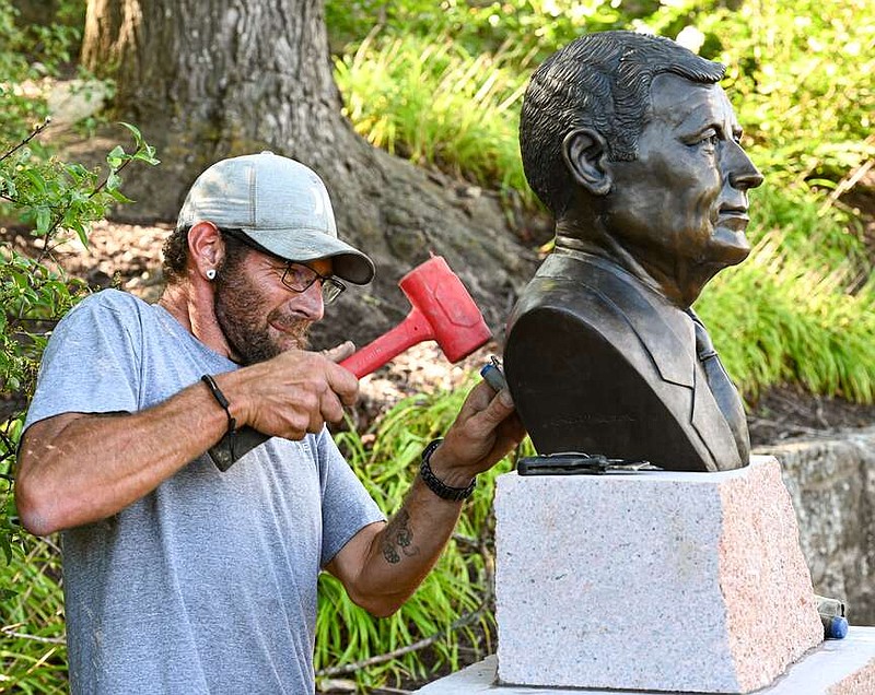 News Tribune file photo: 
Nate Conner taps a strand of lead as he secures the bronze bust of Missouri Gov. Mel Carnahan to its base last August while he and co-workers from Capitol Monuments in Apache Flats installed the monument.
