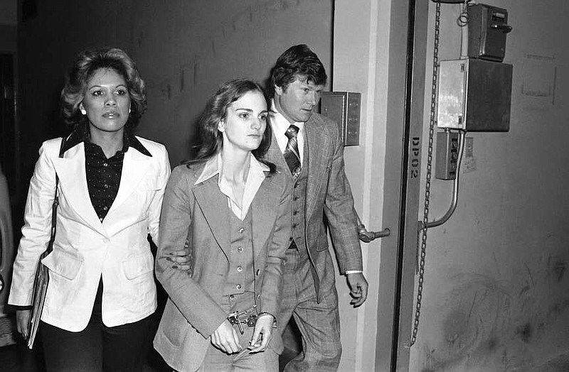 FILE - Accompanied by deputy U.S. Marshal John Brophy, Patricia "Patty" Hearst, center, leaves the Federal building on April 12, 1976, in San Francisco, hours after her sentencing on a bank robbery conviction. The newspaper heiress was kidnapped at gunpoint on Feb. 4, 1974, by the Symbionese Liberation Army, a little-known armed revolutionary group. The 19-year-old college student's infamous abduction in Berkeley, Cali., led to Hearst joining forces with her captors for the 1974 bank robbery. Hearst, granddaughter of wealthy newspaper magnate William Randolph Hearst, will turn 70 on Feb. 20. (AP Photo, File)