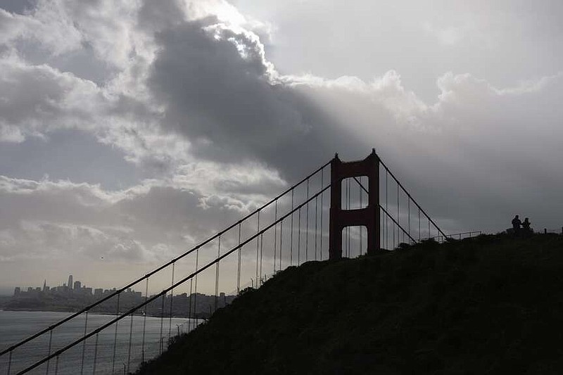 A couple walks in the rain on a pathway by the Golden Gate Bridge near Sausalito, Calif., Monday, Feb. 5, 2024. In Northern California, the storm inundated streets and brought down trees and electrical lines Sunday throughout the San Francisco Bay Area, where winds topped 60 mph (96 kph) in some areas. (AP Photo/Eric Risberg)
