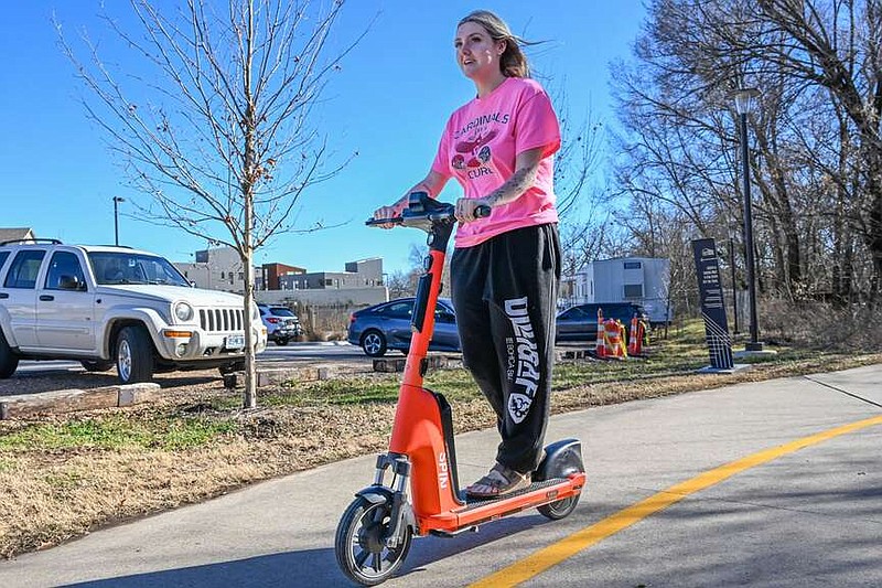 Maddi Douglass rides a Spin scooter Monday on the Razorback Greenway in Fayetteville. The Springdale City Council is considering a proposal to set up Spin bikes and scooters in Springdale. Visit nwaonline.com/photo for today's photo gallery.
(NWA Democrat Gazette/Caleb Grieger)