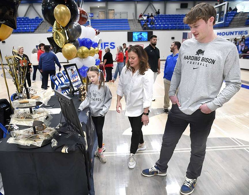Mabry Verser (from right) speaks Wednesday, Feb. 7, 2024, with his mother, Michelle Verser, and cousin, Catherine Lynch, as they decorate a table with a Harding football jersey during a signing ceremony at Rogers High School. Mabry signed a national letter of intent to play football for Harding during the ceremony. The school assembled to celebrate the official signings of football athletes Jacob Jenkins, Dane Williams, Verser, Colin Jones and JT Miller. Visit nwaonline.com/photo for today's photo gallery.
(NWA Democrat-Gazette/Andy Shupe)