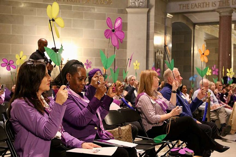 Alexa Pfeiffer/News Tribune photo: 
Attendees of Alzheimer's Advocacy Day hold up flowers to represent the relationship in which their lives are connected to the Alzheimers Association. Families, caretakers and those living with dementia attended the ceremony Tuesday afternoon, Feb. 6, 2024, in the Missouri Capitol Rotunda.