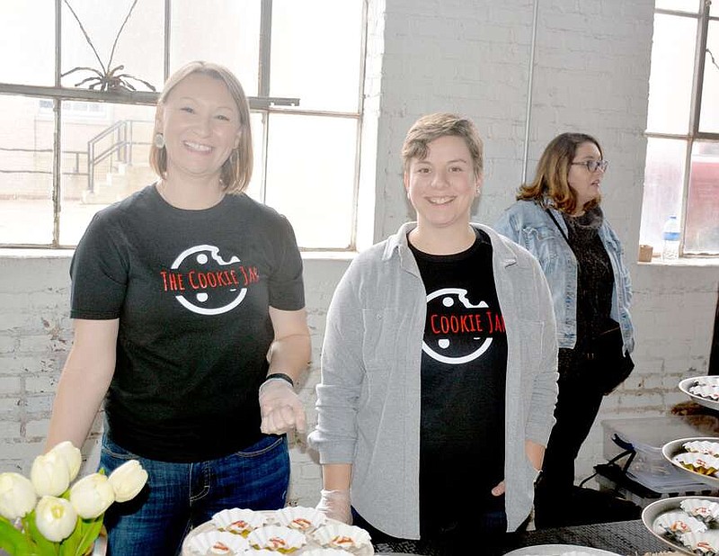 Marc Hayot/Herald-Leader Heather Bryant (left) of the Cookie Jar and her assistant Katlyn Power serve up strawberry cheesecake cookies at Cookie Palooza on Feb. 10 at The Brick Ballroom. The Cookie Jar is a home business in Tontitown.