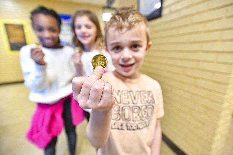 Fulton Thomas (from right), a kindergartener, Edyson Sweeney and Kylee Burress, second-graders, hold gold coins they earned Wednesday to use for a book vending machine at Alma Primary School in Alma. Students can earn coins for their hard work and good behavior, which can then be used to choose a book among the machine's stocked reading materials. Visit rivervalleydemocratgazette.com/photo for today's photo gallery.
(River Valley Democrat-Gazette/Hank Layton)