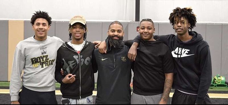 Members of the Hot Springs Trojans football team, from left, Kendall Williams, T.J. Brogdon, head coach Darrell Burnett, Derrion Hawkins, and Octavious Rhodes are pictured following Wednesday's signing at the school's indoor practice facility. (The Sentinel-Record/Donald Cross)