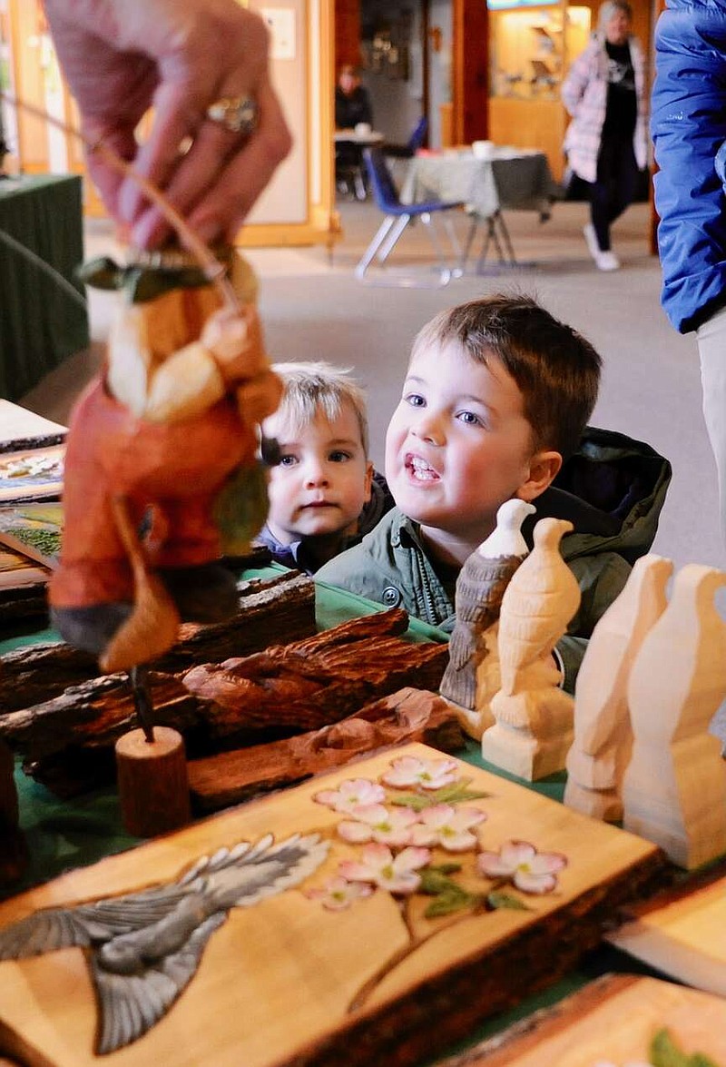 Joe Gamm/News Tribune photo:
Four-year-old Liam Lewis laughs at a carving of Santa, who apparently hooked his britches while fishing. Liam's brother, Nolan, 2, watches his big brother's reaction. The siblings were visiting the Runge Conservation Nature Center in Jefferson City on Saturday, Feb. 10, 2024, as it held an event featuring woodcarvers who specialize in nature.