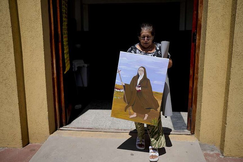 Rita Canteros walks out of a parish church carrying a painting of María Antonia de Paz y Figueroa, more commonly known by her Quechua name of “Mama Antula,” on the outskirts of Buenos Aires, Argentina, Sunday, Jan. 28, 2024. The canonization of “Mama Antula” in a Feb. 11th ceremony to be presided by Pope Francis at St. Peter's Basilica marks the first time a female from Argentina will become saint. (AP Photo/Natacha Pisarenko)