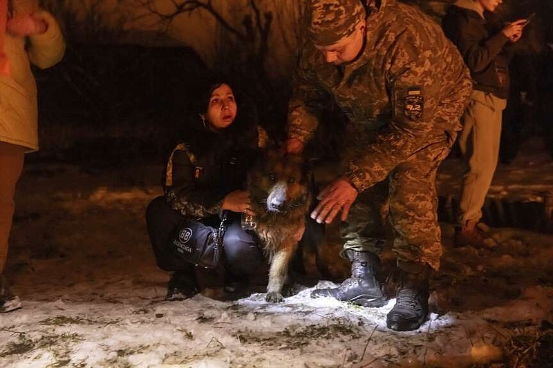 Firefighters rescue a dog as they extinguish a fire following a Russian attack on a residential neighbourhood in Kharkiv, Ukraine, Saturday, Feb. 10, 2024. (AP Photo/Yevhen Titov)