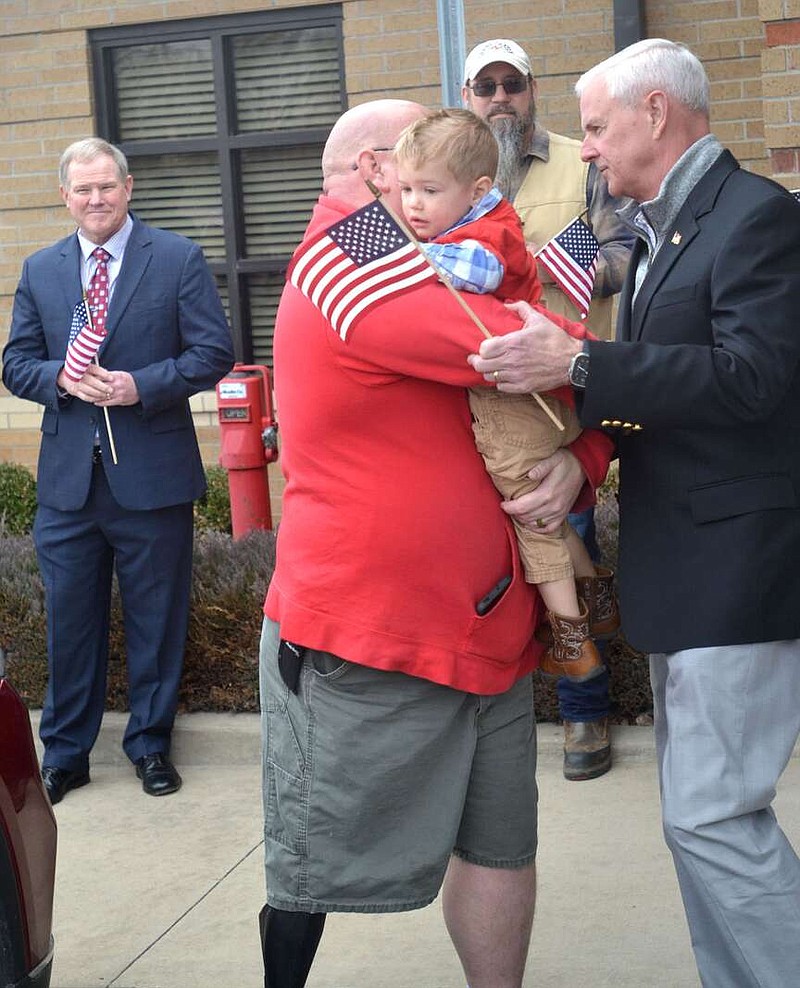 Annette Beard/Pea Ridge TIMES
Veteran Army Sgt. Andrew Butterworth held one of his sons as he visited with U.S. Rep. Steve Womack before the celebration Saturday, Feb. 10, in Pea Ridge City Hall. Standing behind them holding an American flag was retired Major General Kendall Penn, secretary of the Arkansas Department of Veterans Affairs. For more photographs, go to the PRT gallery at https://tnebc.nwaonline.com/photos/.