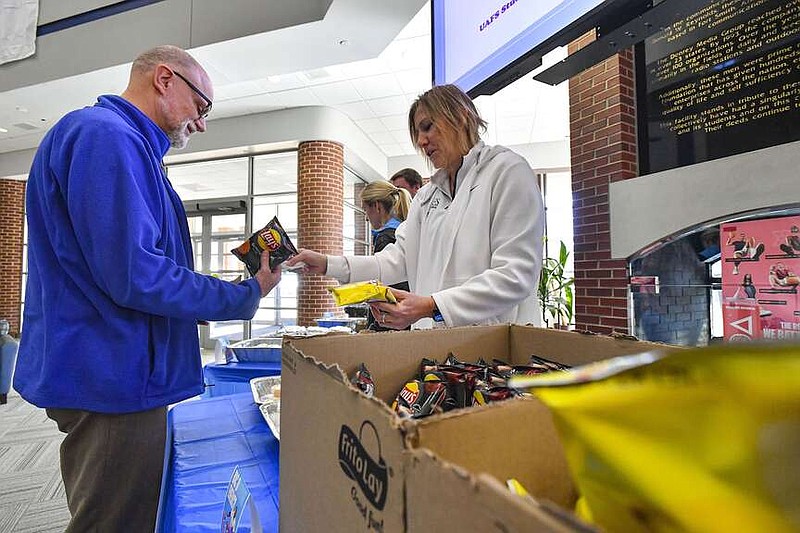 Jane Sargent (right), head coach of the University of Arkasas-Fort Smith volleyball team, hands out free food to Dr. Lee E. Krehbiel, vice chancellor for enrollment management and student affairs, and others, Tuesday, Feb. 13, 2024, during a campus cookout as part of homecoming week inside the Smith-Pendergraft Campus Center on the UAFS campus in Fort Smith. The university kicked off the week of homecoming activities, the theme for which is “Where Memories Roar,” with a prep rally Monday night. The festivities continue today with an intramural championship, women's and men's basketball games against St. Edward's on Thursday, and a dance on Friday evening. Homecoming will cap off Saturday with a lunch tailgate, followed by the Lady Lions and Lions hosting St. Mary's. A crowning ceremony will take place at halftime of the men's game. Visit rivervalleydemocratgazette.com/photo for today's photo gallery.
(River Valley Democrat-Gazette/Hank Layton)