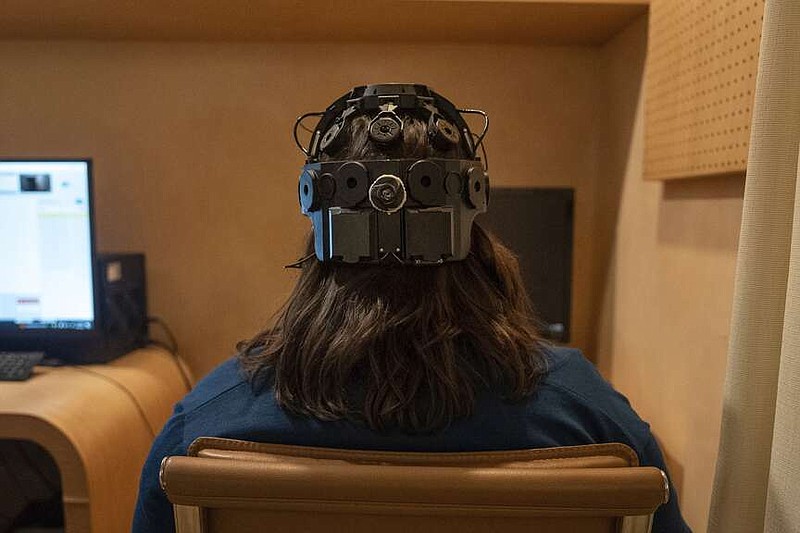 Emily Hollenbeck, a deep brain stimulation therapy patient, demonstrates an EEG device that records brain activity as she reacts to short videos at Mount Sinai's “Q-Lab” in New York on Dec. 20, 2023. Dr. Brian Kopell, who directs Mount Sinai's Center for Neuromodulation, says in normal brains electrical activity reverberates unimpeded in all areas, in a sort of dance. In depression, the dancers get stuck within the brain's emotional circuitry. DBS seems to “unstick the circuit,” he says, allowing the brain to do what it normally would. (AP Photo/Mary Conlon)