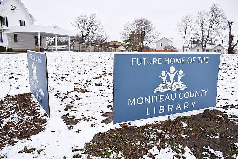 Democrat photo/Garrett Fuller — Three-tenths of an inch of snow is seen Friday blanketing the site of Moniteau County Library's future home at 209 S. Oak St., along with a new addition promoting the project. The signs were installed Dec. 21. A space is left between the two signs for a conceptual drawing of the planned facility once completed by architects at Sapp Design Architects.