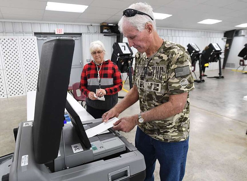 Kim Clifton (right) of Washington County places his ballot Wednesday into a machine as poll worker Karen Lockhart of Hogeye assists after Clifton voted at the West Fork Community Center. Early voting continues this week ahead of the March 5 primary and judicial election. Visit nwaonline.com/photo for today's photo gallery.

(NWA Democrat-Gazette/Andy Shupe)