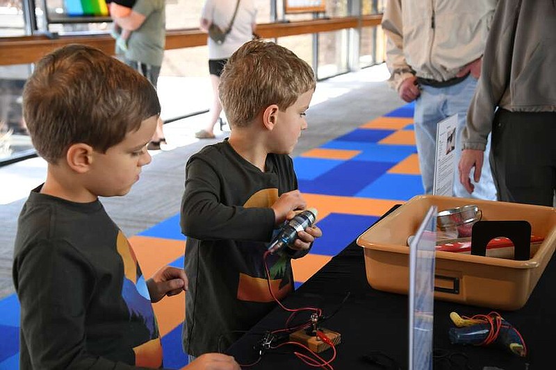 Two brothers work together to complete an experiment at the discovery table during the first Science Saturdays last weekend. (The Sentinel-Record/Lance Brownfield)