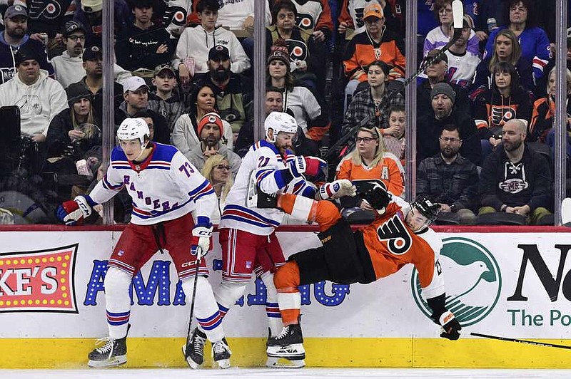 Philadelphia Flyers' Sean Walker, right, is checked by New York Rangers' Matt Rempe (73) and Barclay Goodrow (21) during the second period of an NHL hockey game, Saturday, Feb. 24, 2024, in Philadelphia. (AP Photo/Derik Hamilton)